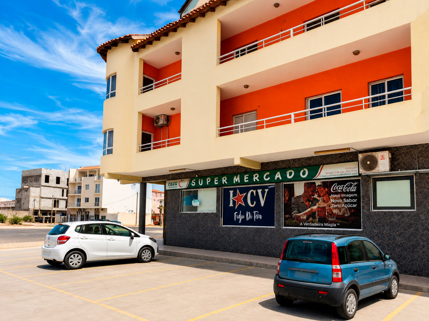 Cars parked outside a supermarket beneath residential apartments in Santa Maria, Sal Island
